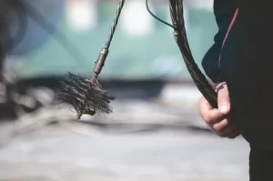 Chimney sweep brush held by technician, emphasizing chimney maintenance and safety services by Paragon Chimney and Roofing.