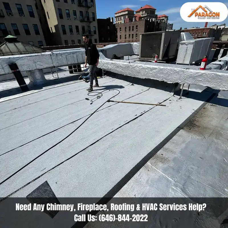 Roofing technician performing regular roof maintenance on a flat commercial rooftop in New York City.