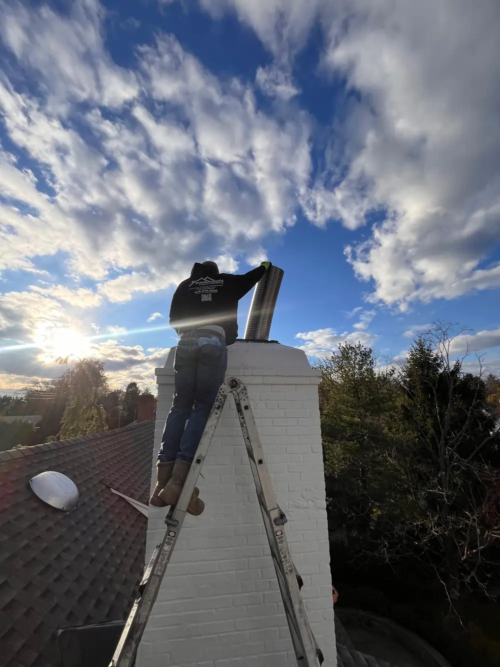 Technician installing a chimney liner on a residential rooftop, demonstrating compliance with the 3-2-10 chimney rule for safe venting.