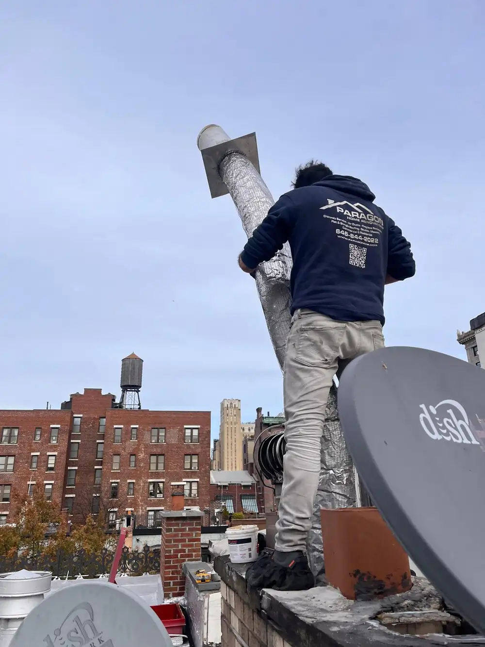 Technician installing a metal chimney liner on a rooftop, ensuring proper chimney draft height in New York for safe and efficient venting.