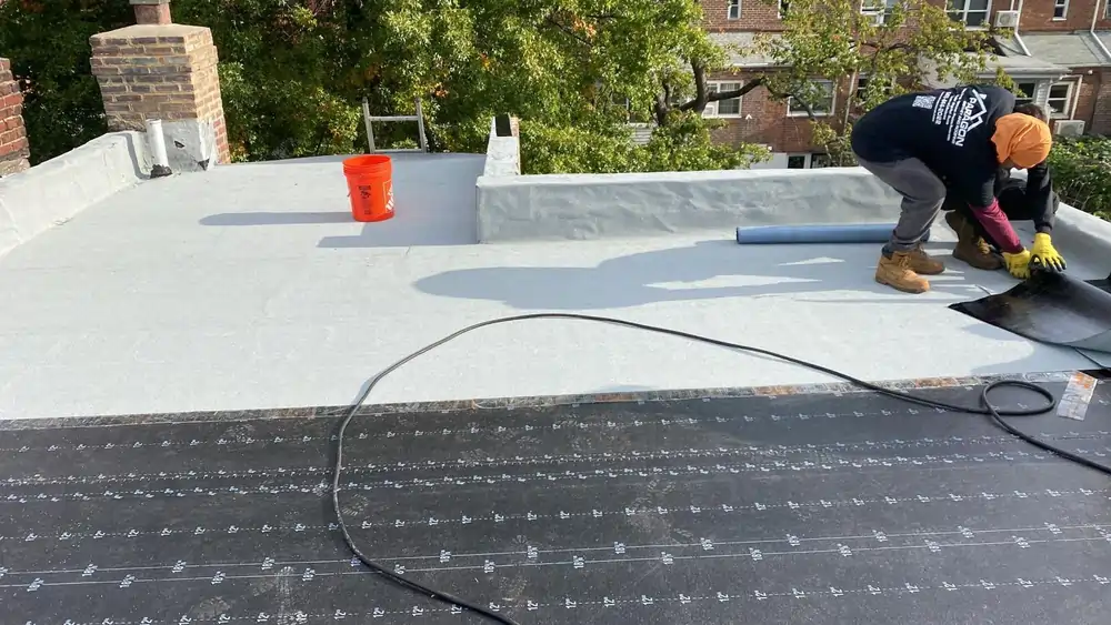 Roofing professional installing a flat roof membrane on a residential home, demonstrating one of the best roof style for homes in New York.